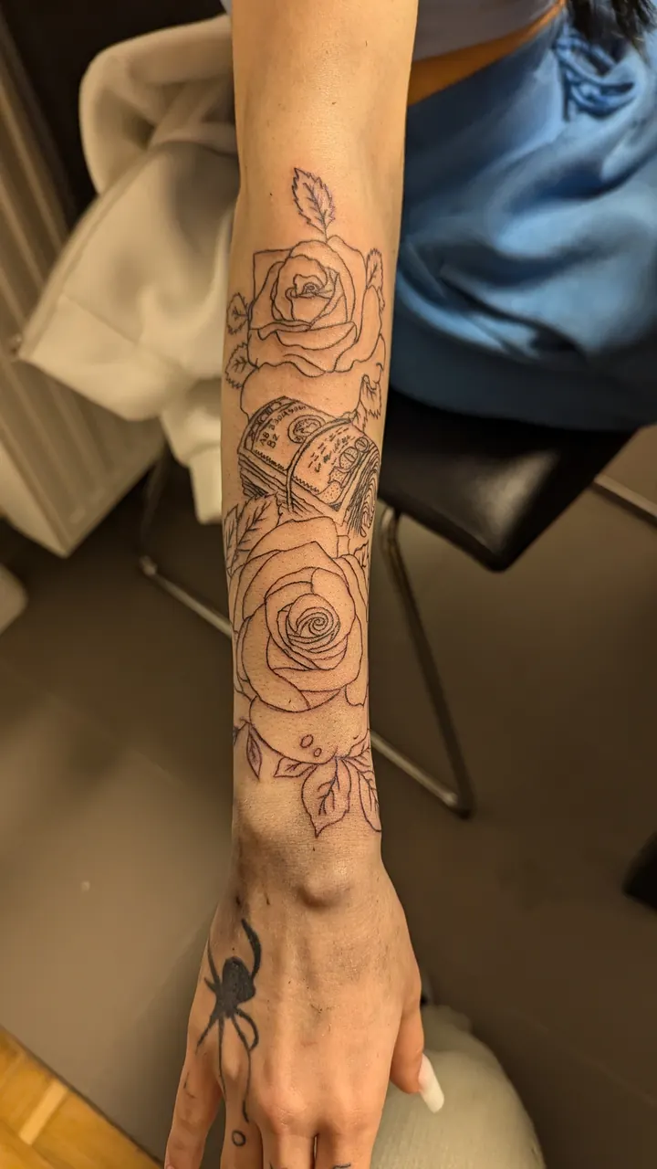 Roses down the forearm with a spider on the hand